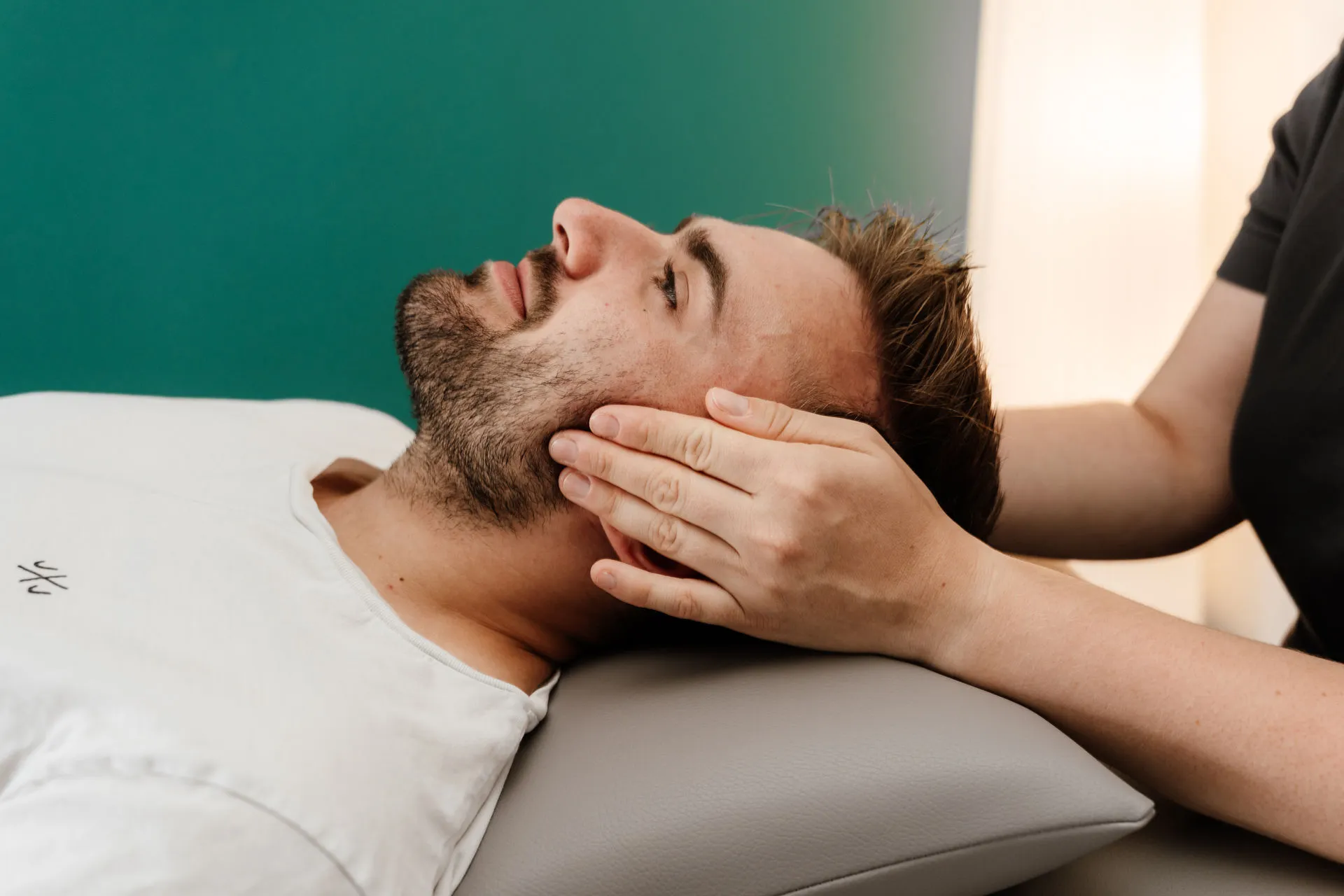 Zwei H&auml;nde am Kopf einer Patienten w&auml;hrend einer Kiefergelenkstherapie&nbsp;