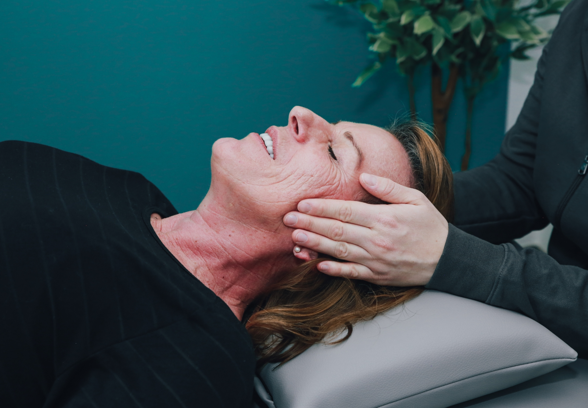 Zwei Hände am Kopf einer Patientin während einer Kiefergelenkstherapie 